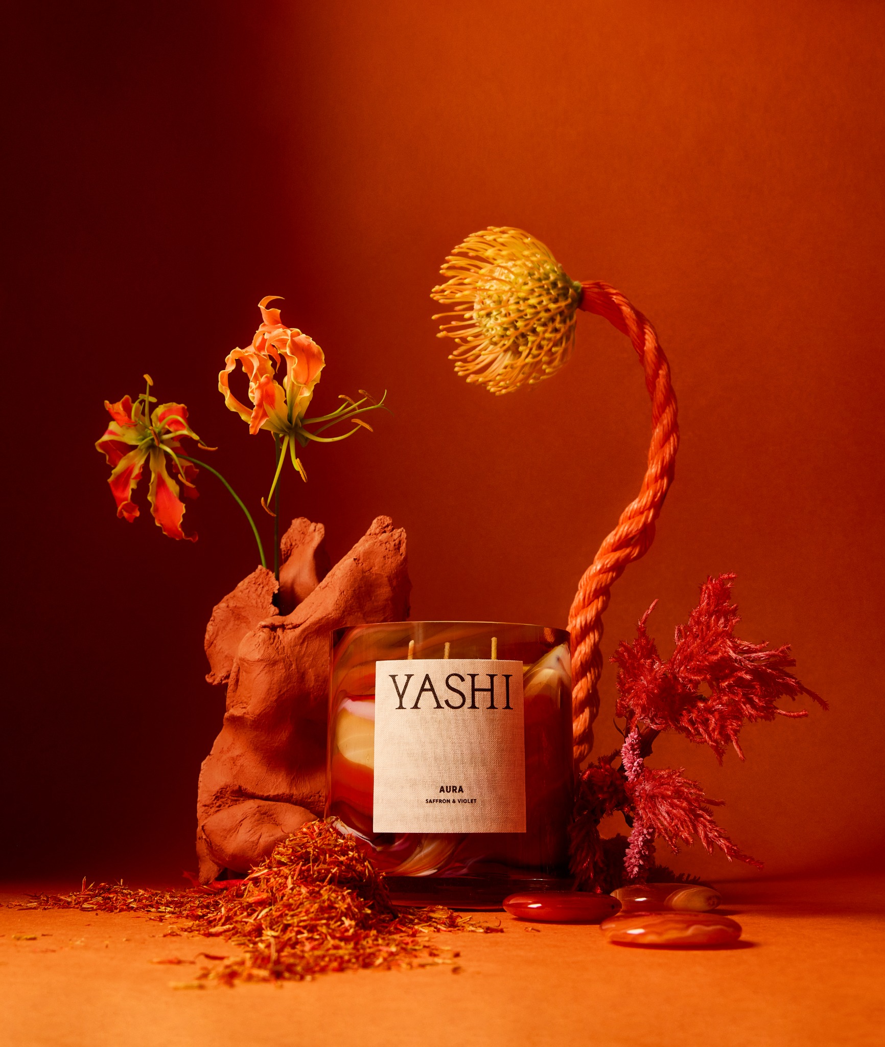 La bougie Aura de Yashi dans un décor floral aux tonalités rouge profond